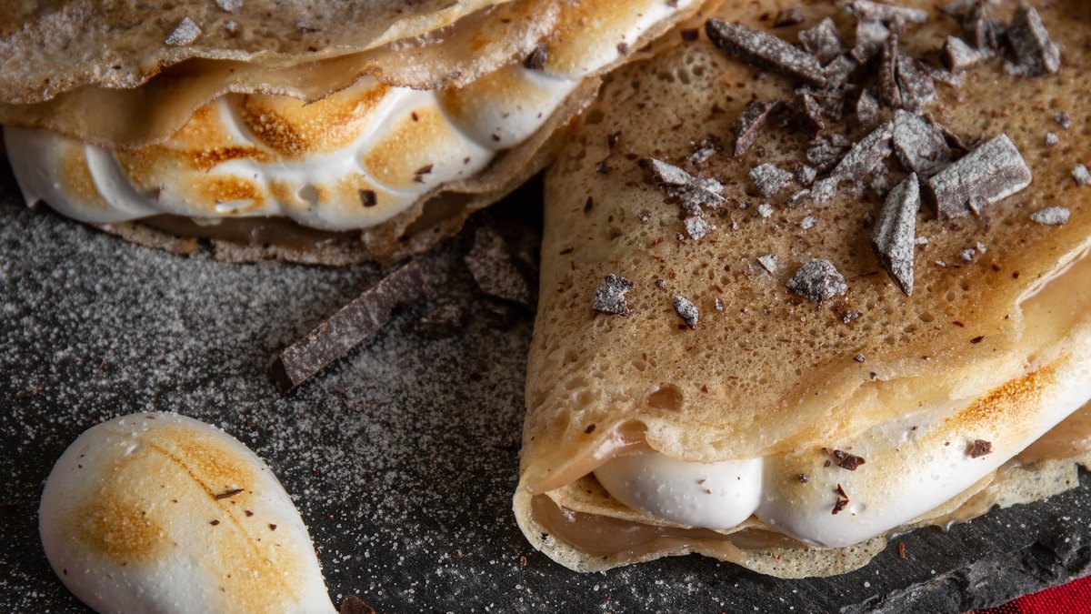 Crepes senza uova IN-VECE piegate su ardesia, con meringa, scaglie di cioccolato e zucchero a velo