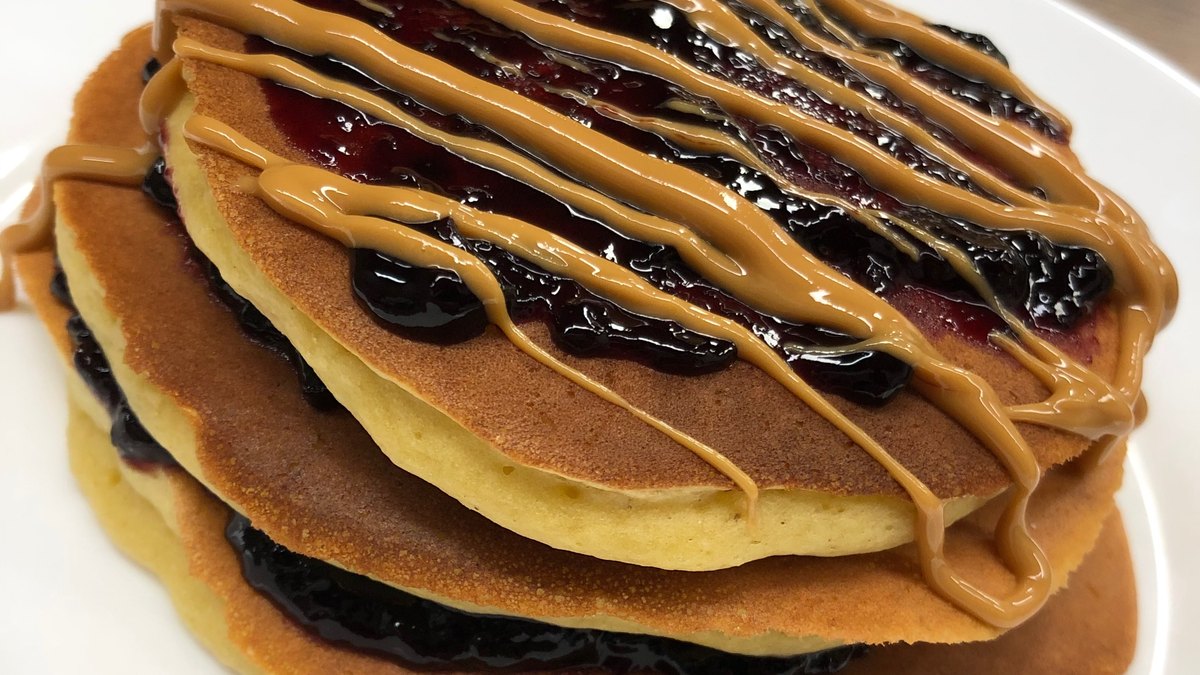 Pila di pancake senza uova IN-VECE con confettura di frutti di bosco e colata di crema